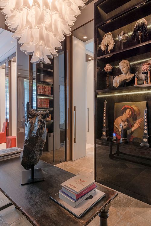 Détail du cabinet de curiosités à Saint-Germain-des-Prés avec tête de cheval en bronze, lustre sculptural en verre et étagères illuminées. Photographie d'architecture intérieure par Nicolas Karadimos.