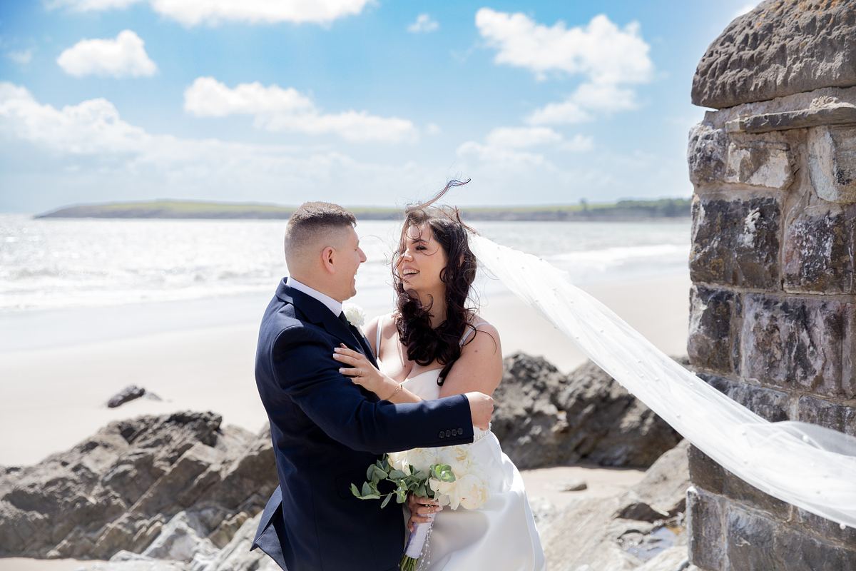 Bride and groom standing together beside a stone wall near the coast at Barry Island, South Wales, photo by Marta Vershynina, South Wales wedding photographer