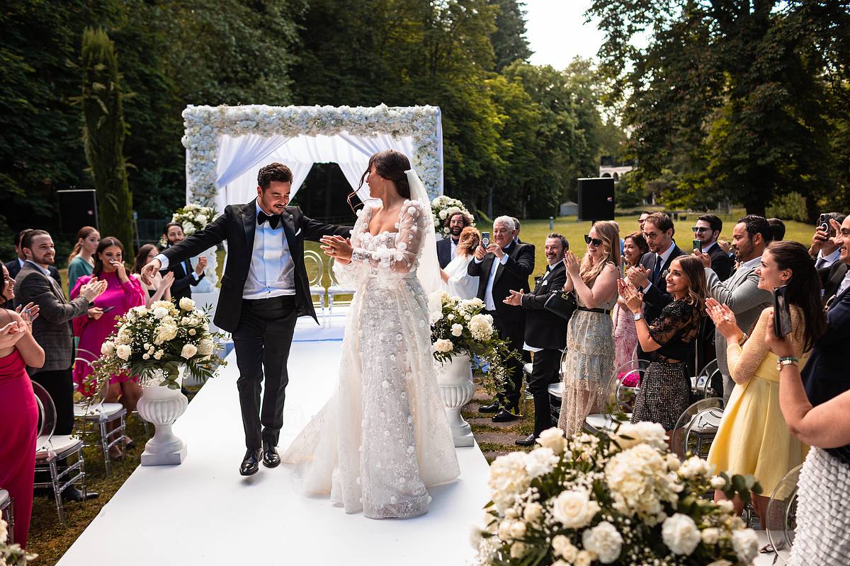 Sebastien CLAVEL Photographe mariage Lyon Les mari&eacute;s c&eacute;l&egrave;brent leur union avec joie en marchant sous une arche de mariage, entour&eacute;s par les acclamations et les applaudissements de leurs amis et de leur famille