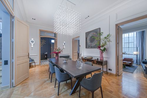 Salle à manger haussmannienne sur les Champs-Élysées avec table noire, chaises bleues et lustre cascade en cristal. Photographie d’architecture intérieure par Nicolas Karadimos.