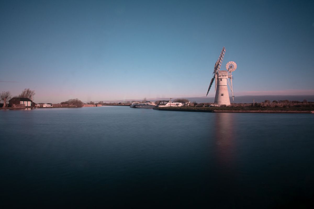 Thurne Mill reflected in calm water on a cold morning in the Norfolk Broads, England.