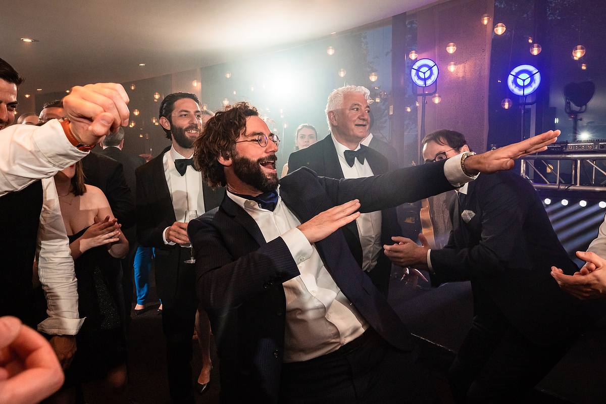 Un chanteur dynamique met l'ambiance avec une performance enflamm&eacute;e, tandis que les mari&eacute;s et les invit&eacute;s dansent et l&egrave;vent les bras en rythme, un moment m&eacute;morable au Pavillon du Casino Lyon vert par Sebastien CLAVEL Photographe mariage Lyon