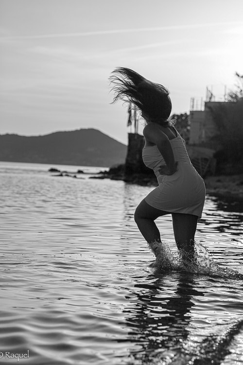 Jeune femme sautant dans l’eau en noir et blanc.