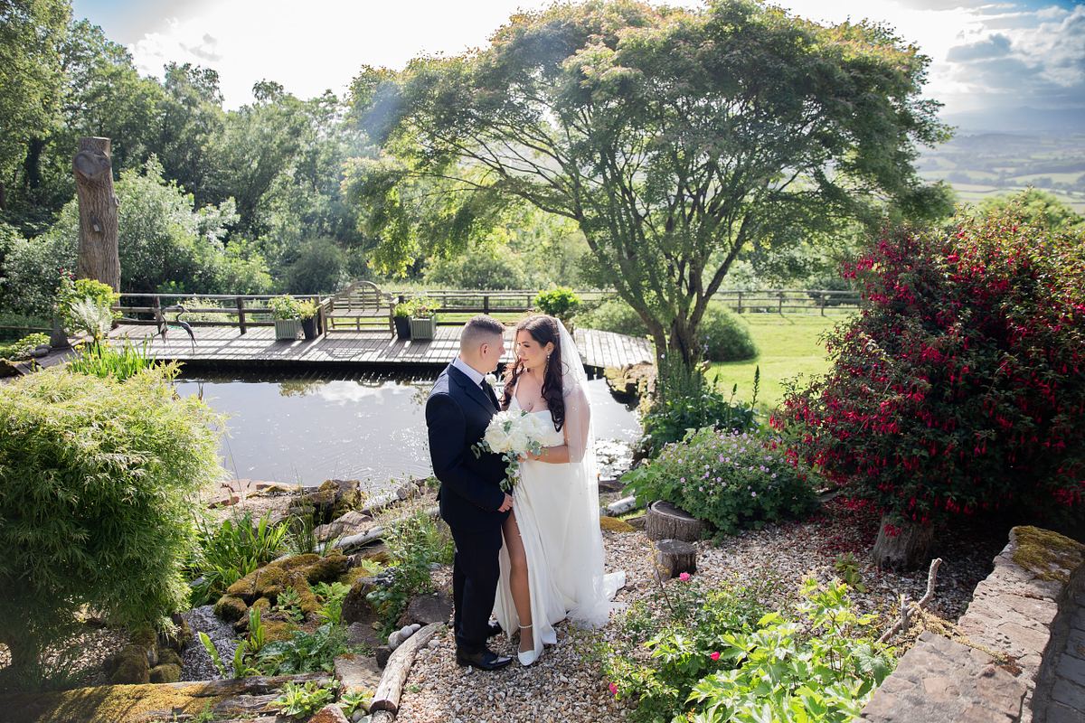 Bride and groom standing together in a colourful garden in South Wales