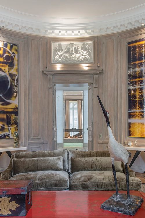 Salon circulaire haussmannien à Saint-Germain-des-Prés avec canapé en velours, sculpture de grue et moulures au plafond. Photographie d'architecture intérieure par Nicolas Karadimos.