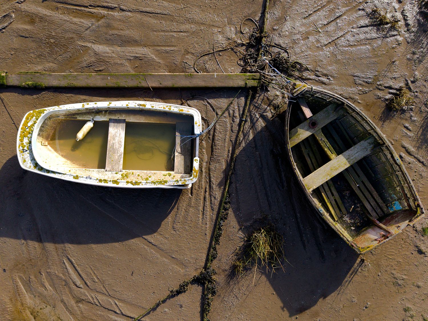 aerial drone photograph of two weathered boats resting on exposed mudflats during low tide.