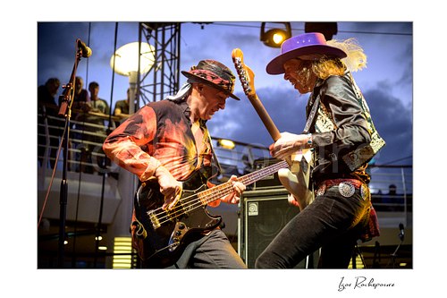 Horizontal color image of Ufo Walter and Randy Hansen performing together on an outdoor ship deck stage under warm concert lights