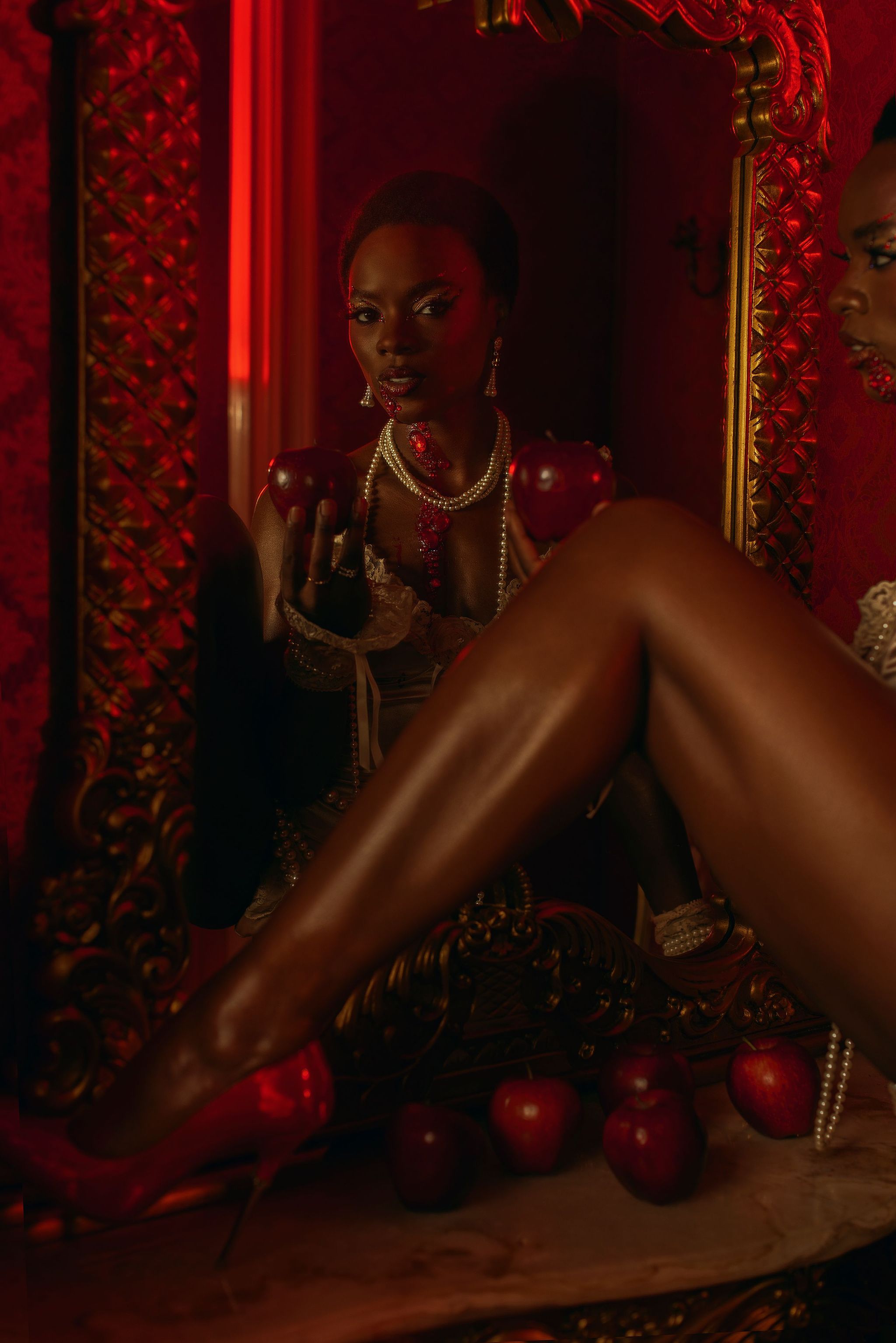 Beautiful black woman with natural hair bathed in red light looking in mirror by copenhagen photographer