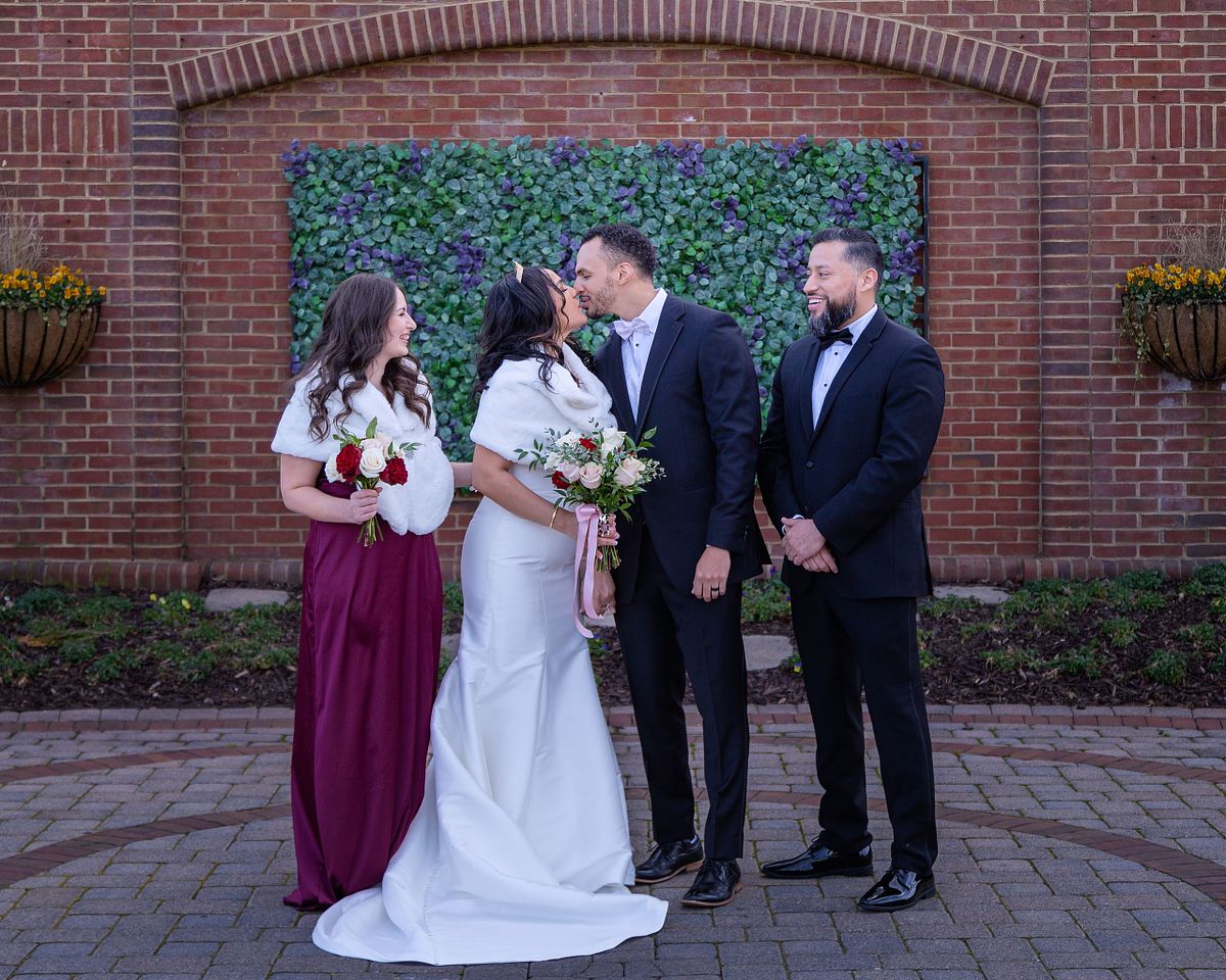 bride and groom kissing with the best man and maid-of-honour smiling at baywood weddings