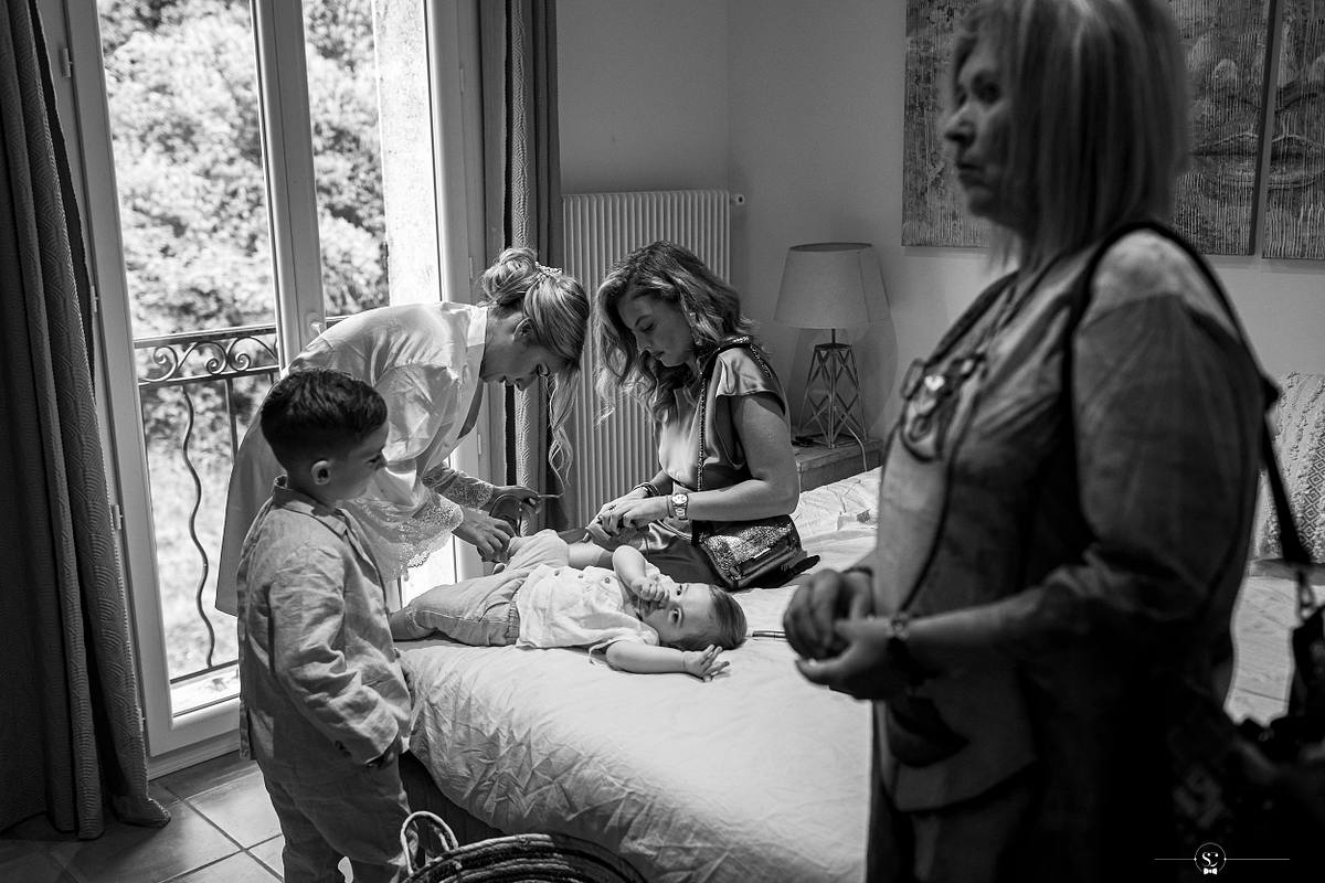 Dans une atmosph&egrave;re intime, un enfant joue avec des brosses &agrave; cheveux sur le lit, tandis que la mari&eacute;e et les invit&eacute;es se pr&eacute;parent, sc&egrave;ne captur&eacute;e par S&eacute;bastien Clavel lors d'un mariage &agrave; N&icirc;mes
