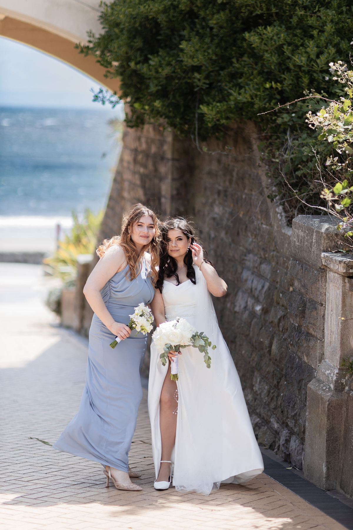 Bride with bridesmaid beside the seafront at Barry Island, South Wales