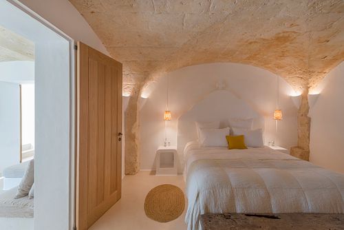 Chambre voûtée en pierre d’une finca d’agrotourisme à Santa Ponça, Minorque, avec lit et ambiance chaleureuse. Photographie par Nicolas Karadimos.