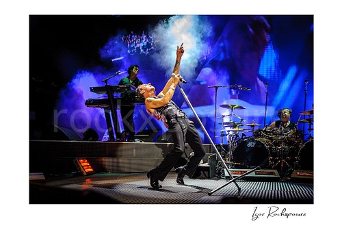Horizontal color image of Depeche Mode members Peter Gordeno, Dave Gahan, and Christian Eigner performing on stage
