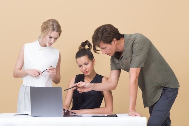 man onderwijst vrouw terwijl hij naar grijze laptop wijst