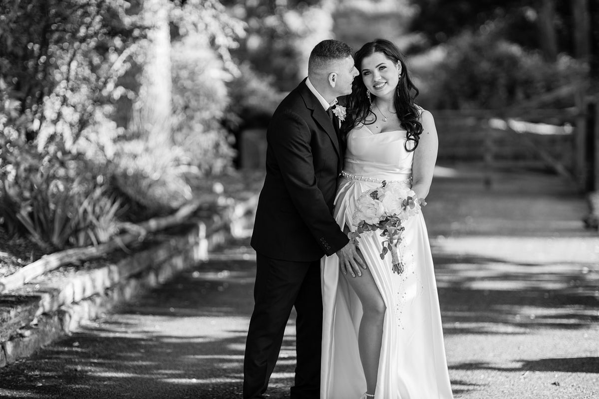 Black and white portrait of groom embracing smiling bride outdoors in South Wales