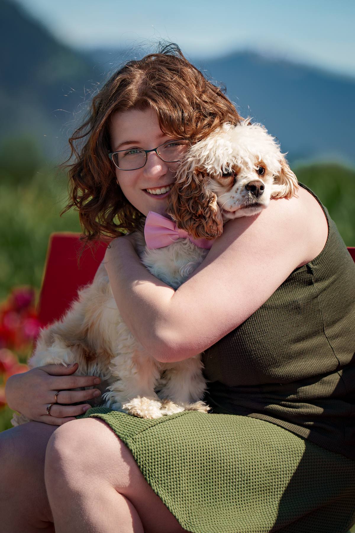 Young woman with her cocker spaniel sitting on a bench at park.