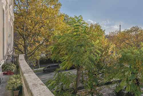 Vue depuis le balcon d’un appartement haussmannien de 1880 à la Place de l’Etoile, Paris, sur les arbres en fleurs et la Tour Eiffel au loin. Photographie d’architecture intérieure par Nicolas Karadimos.