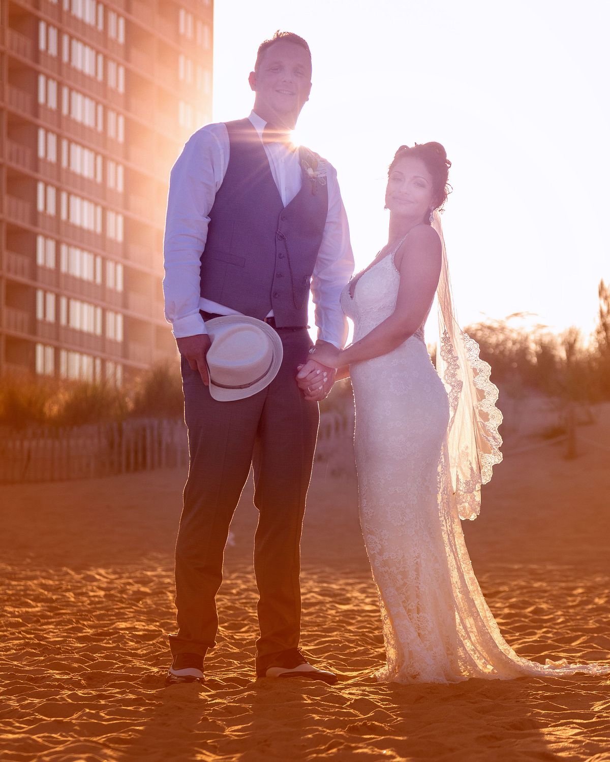 bride and groom during sunset hours, with the sun setting behind them on the beach in sussex county, de