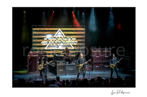Horizontal color image of Stryper performing live with Timothy Gaines, Robert Sweet, Michael Sweet, and Oz Fox on stage