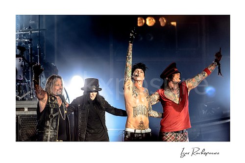 Horizontal color image of Mötley Crüe performing live on stage with Vince Neil, Mick Mars, Tommy Lee and Nikki Sixx under bright concert lighting