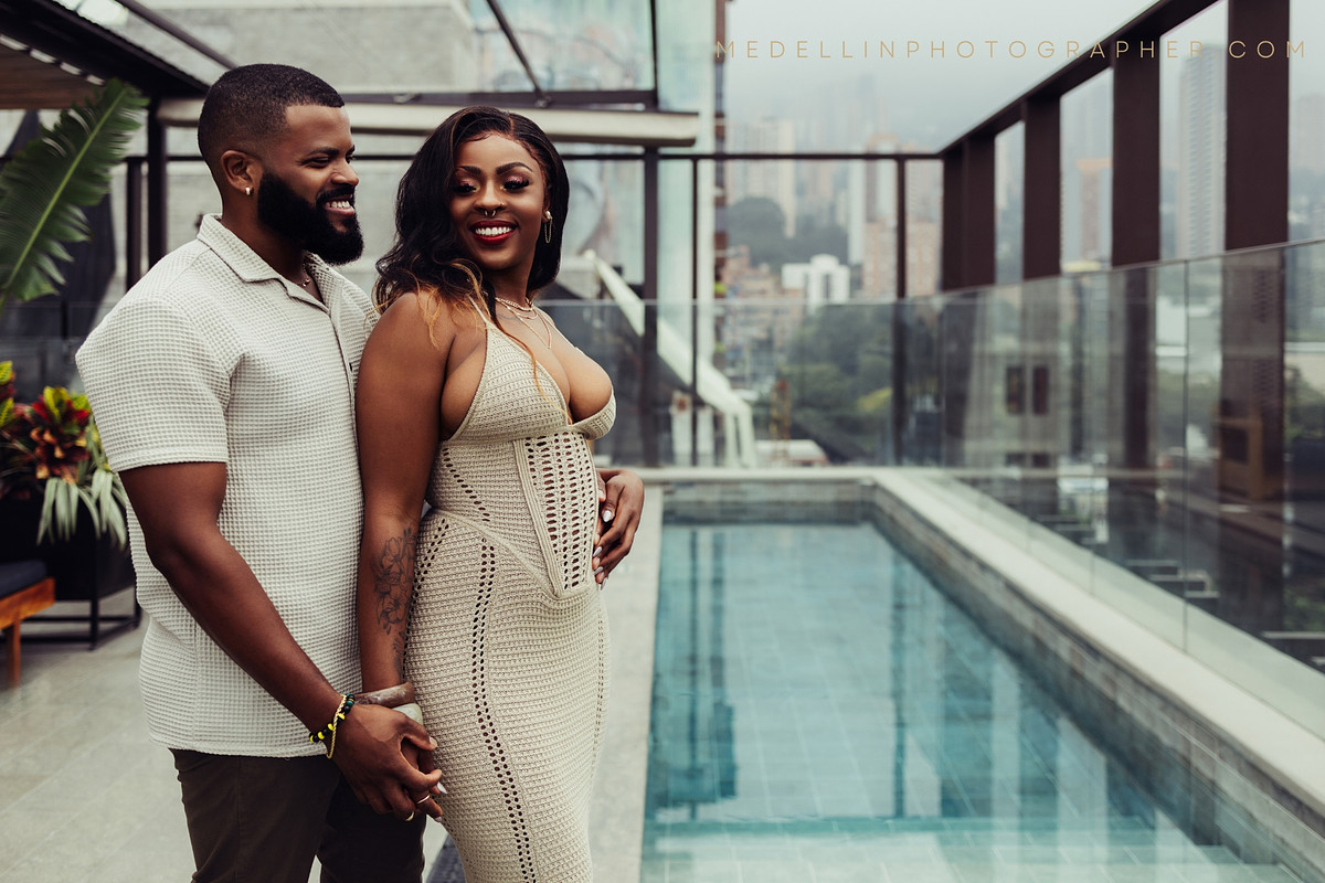 Rooftop pool engagement portrait with the El Poblado skyline behind the couple