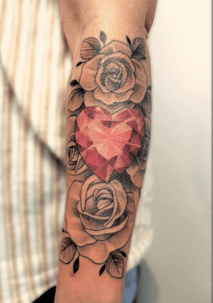 Neotraditional tattoo featuring a pink heart gem surrounded by black and grey roses, detailed shading and ornamental design, created in Stoke-on-Trent by Alika Tattoo Art.