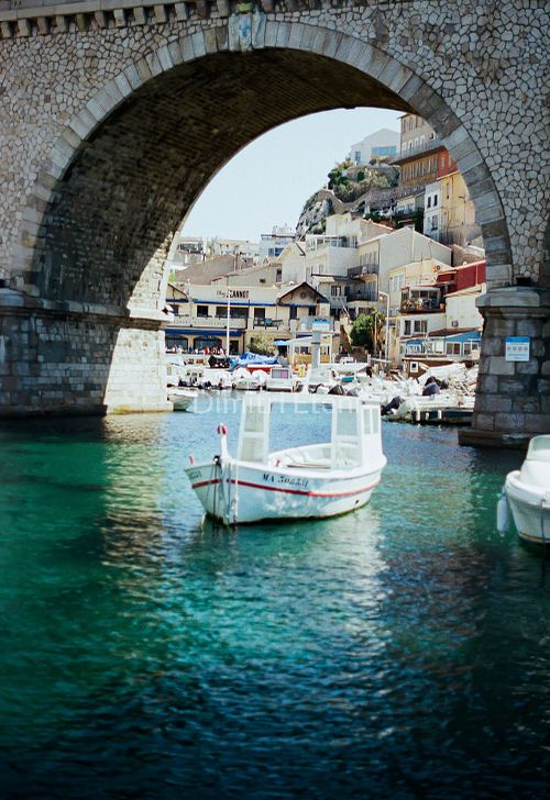 Photographie argentique d’un bateau dans le Vallon des Auffes à Marseille, encadré par l’arche du pont, par Dimitri Eteni