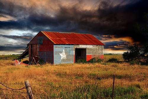 A texas flag barn in rural texas with drama filled storm clouds in the background
