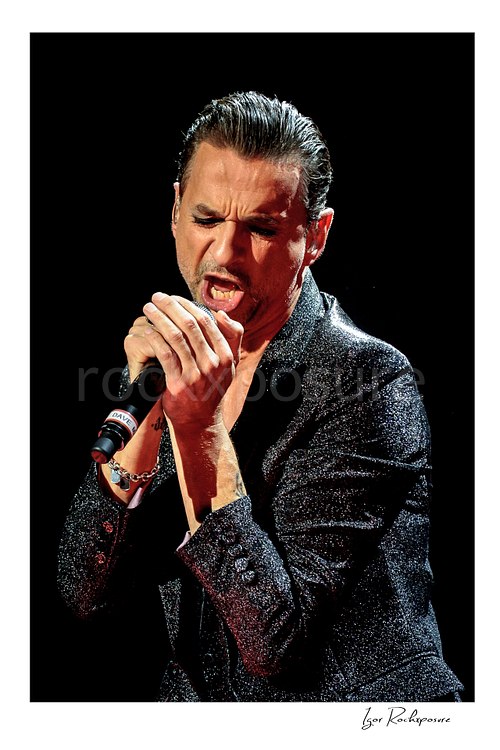 Vertical color image of Depeche Mode singer Dave Gahan singing into a microphone during a live performance