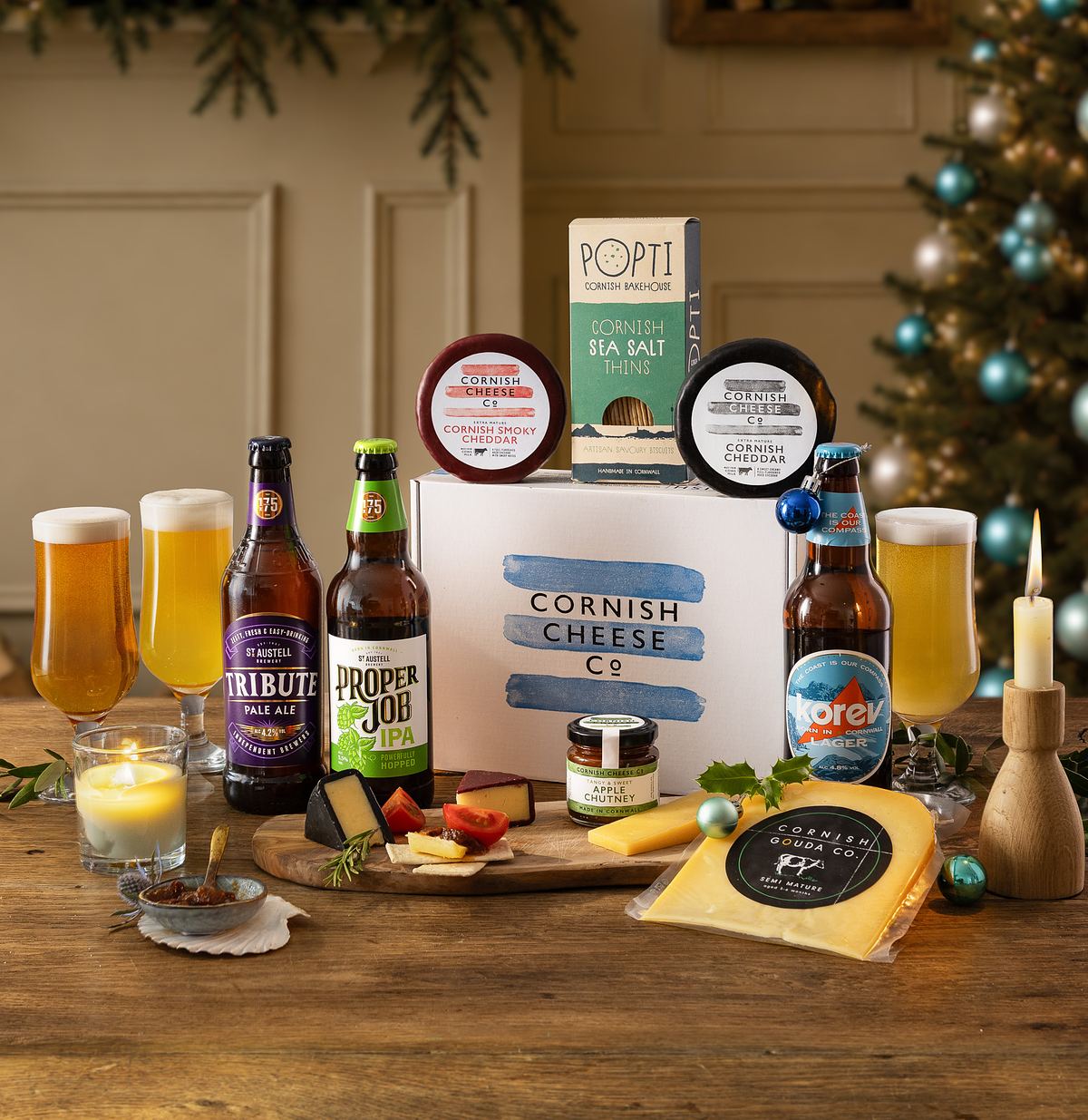 A selection of Cornish cheeses, crackers, and bottled beers on a table with a festive setting