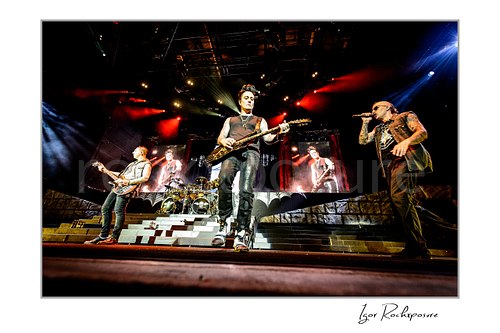 Horizontal color image of Zacky Vengeance, Synyster Gates, and M. Shadows of Avenged Sevenfold performing on stage under red and blue concert lights