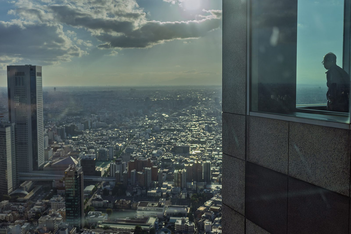 Vue sur Tokyo depuis les fenêtres du Tokyo Metropolitan Government Building, une silhouette au bord de la vitre