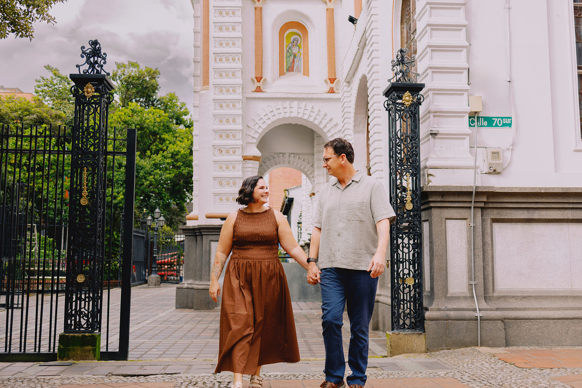 Couple in front of the white church tower on the main park in Sabaneta