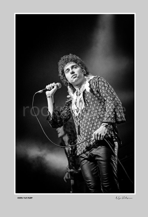 Vertical black and white image of Greta Van Fleet singer Josh Kiszka holding a microphone during a live performance