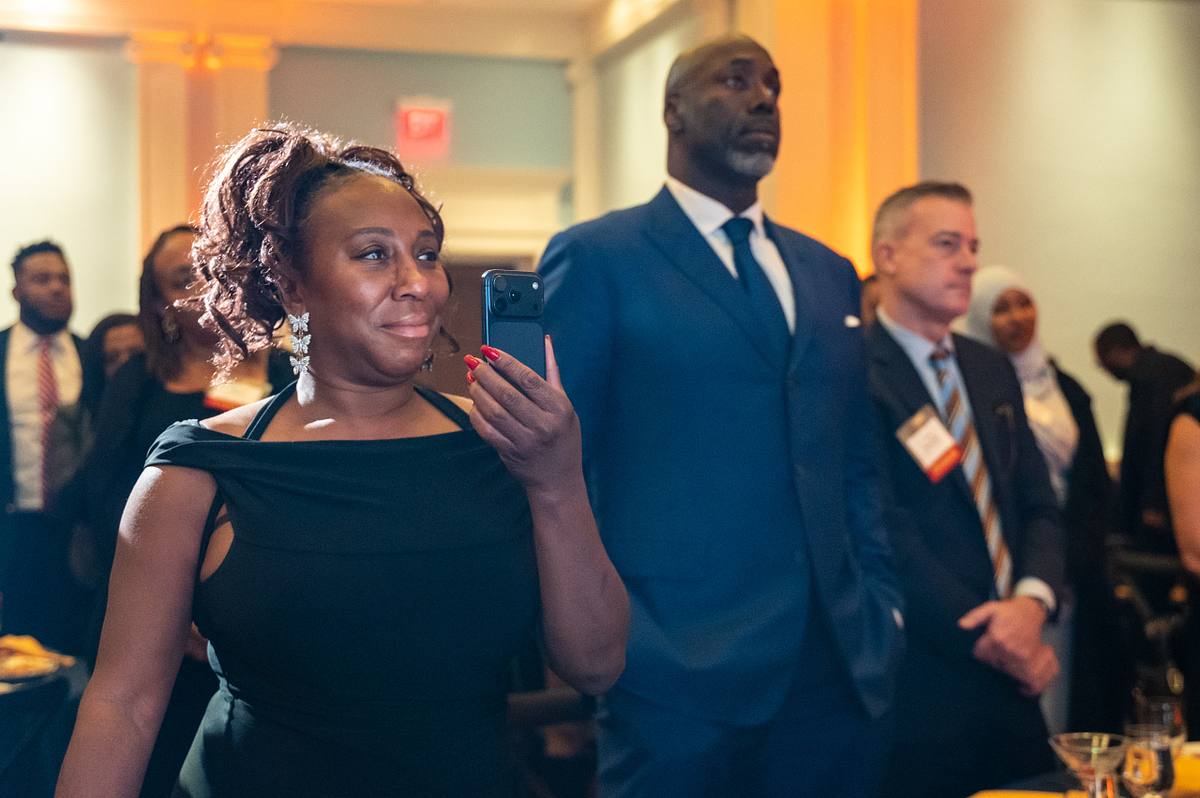 A guest in a black dress holds up her phone among standing attendees at Launch of Philadelphia’s 40th Anniversary Gala reception.