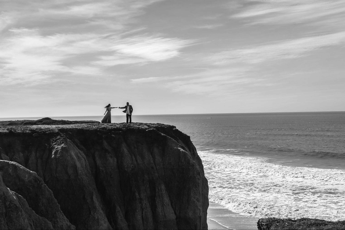 Imagen de dos modelos posando en un acantilado junto al mar.