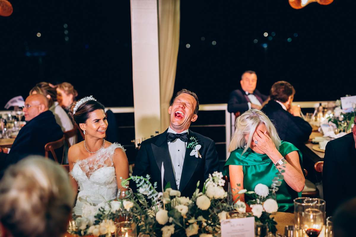 Bride and groom laughing with a guest during the wedding dinner