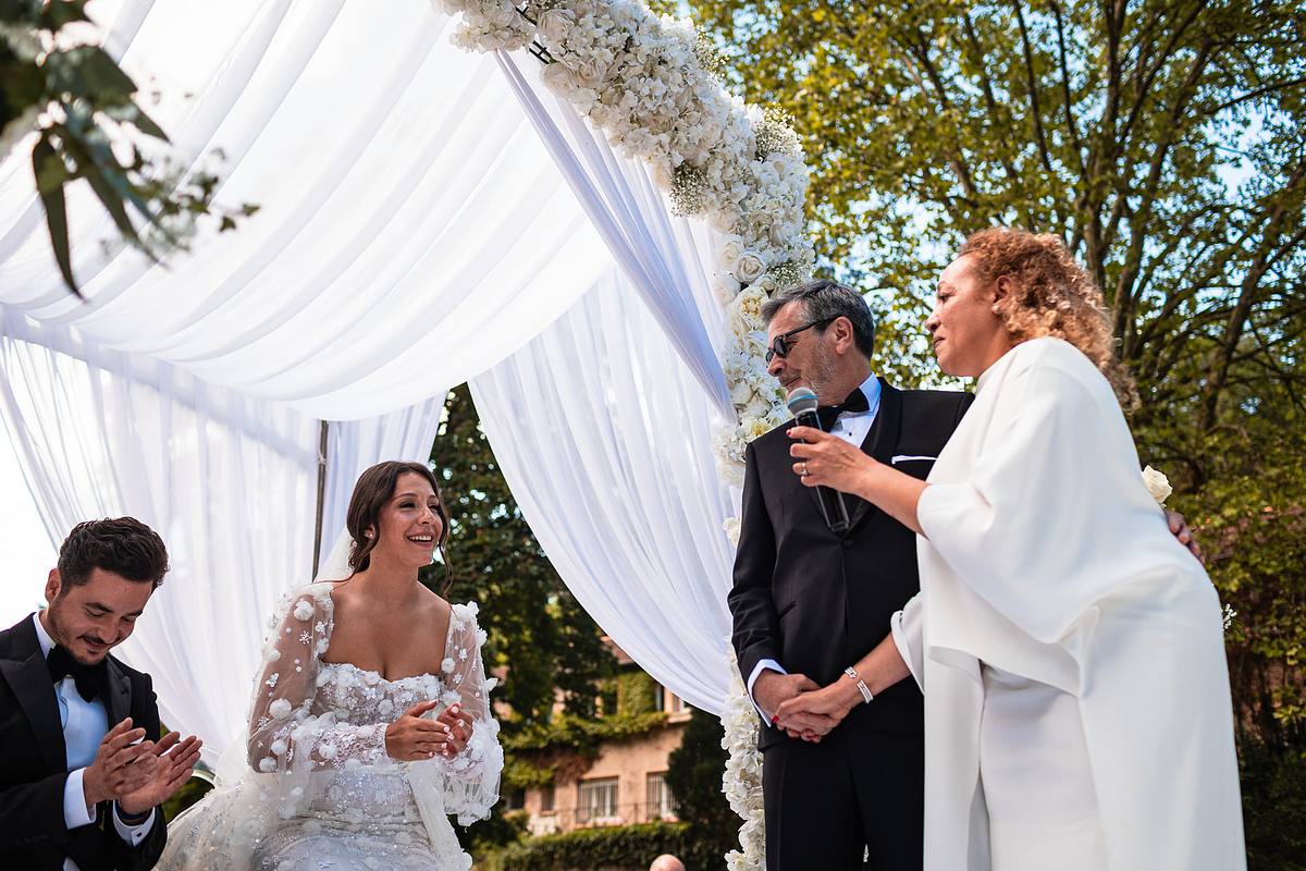 la maman de la mari&eacute;e partage un moment joyeux avec les mari&eacute;s sous un dais floral, une photo de Sebastien Clavel &agrave; l'Hotel Pavillon de Lyon