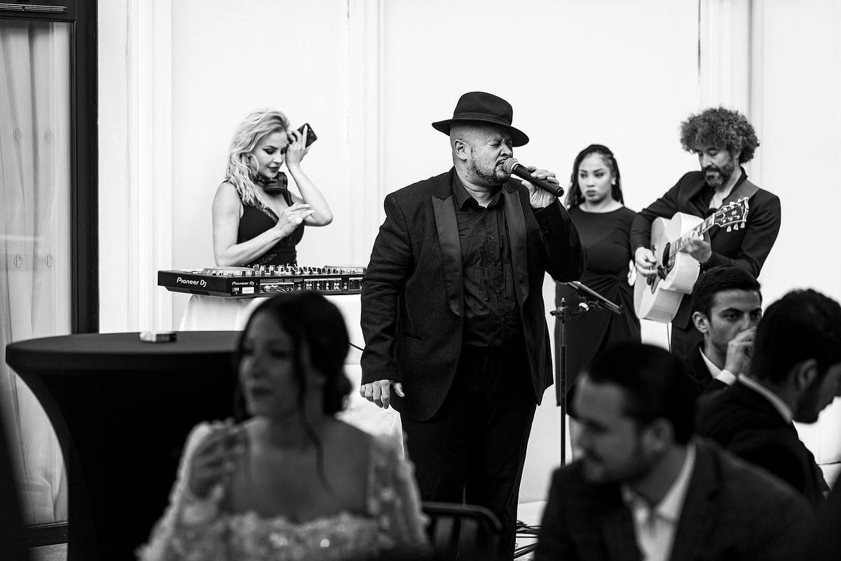 Un instantan&eacute; en noir et blanc o&ugrave; le chanteur du 'Groupe Love' captive l'audience avec une performance dynamique, tandis qu'un guitariste l'accompagne discr&egrave;tement, immortalis&eacute; par Sebastien CLAVEL Photographe mariage Lyon