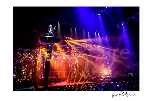 Horizontal color image of Chris Caffery of Trans Siberian Orchestra performing on a raised platform above a brightly lit concert stage