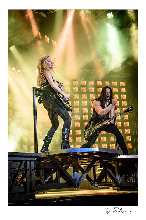 Vertical color image of Trans Siberian Orchestra performers on stage with guitars, dramatic smoke, and bright concert lighting