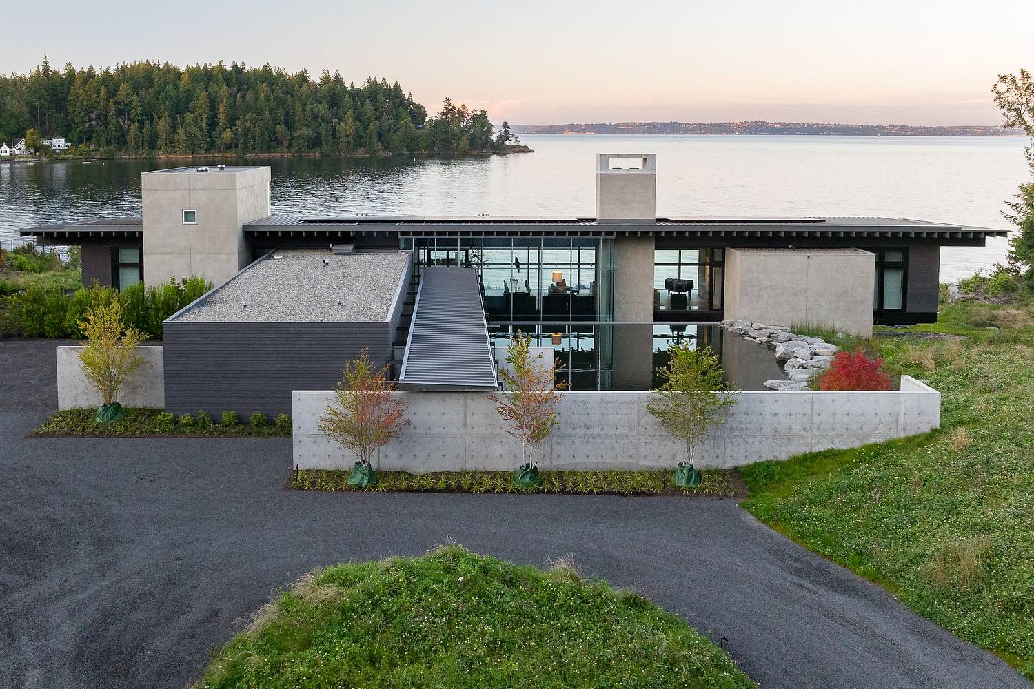 Modern waterfront home with concrete and dark steel exterior photographed at dusk, luxury architecture photography by Jonathan Marks