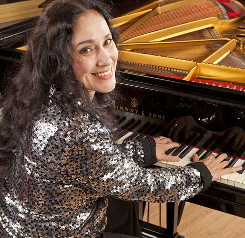 Myriam Birger at the piano during a photoshoot, smiling at the instrument