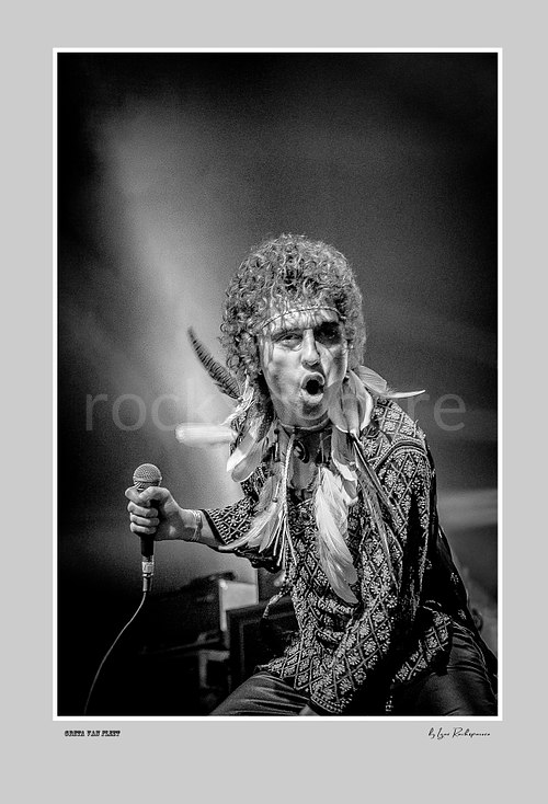 Vertical black and white image of Greta Van Fleet singer Josh Kiszka holding a microphone during a live performance