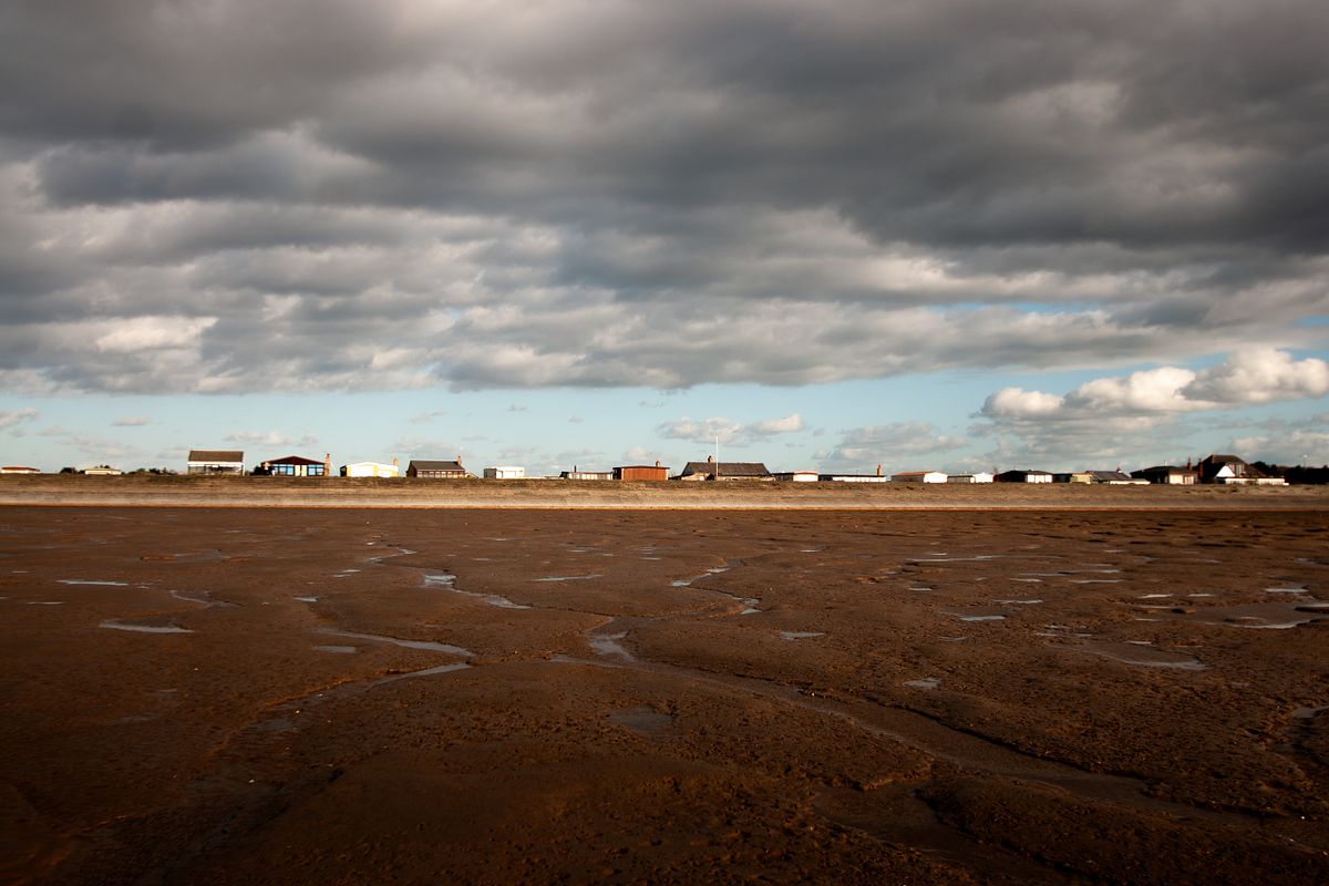 The wide open coastal landscape at Snettisham, Norfolk, beneath a dramatic sky.