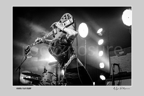 Horizontal black and white image of Greta Van Fleet guitarist Jake Kiszka performing live on stage with his guitar raised overhead