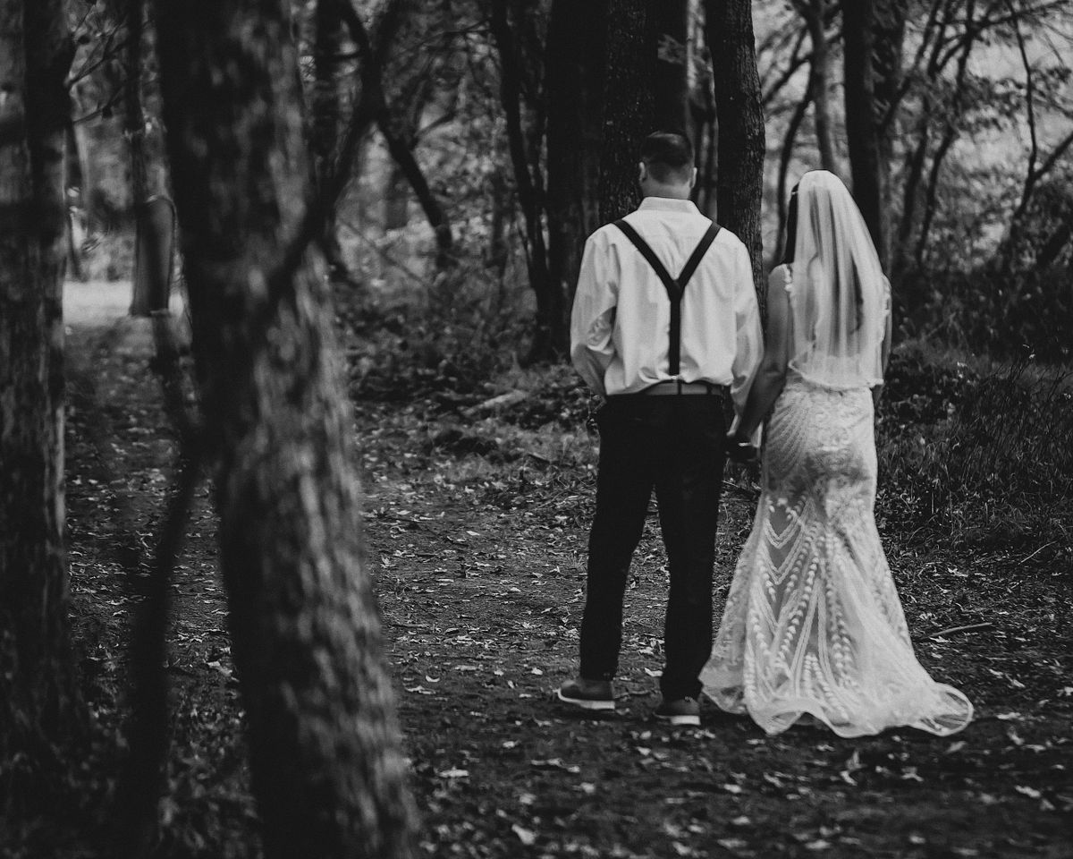 black and white of bride and groom walking through the forest after the ceremony in Salisbury, md