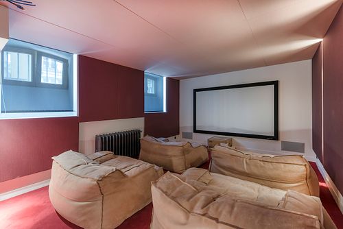 Salle de cinéma privée avec poufs en cuir et écran géant dans un appartement haussmannien sur les Champs-Élysées, Paris. Photographie d’architecture intérieure par Nicolas Karadimos.