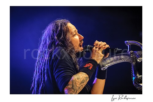 Horizontal color image of Korn singer Jonathan Davis singing into a microphone beside a distinctive stage microphone stand