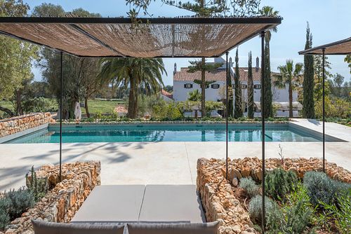 Piscine extérieure avec pergola en roseau et vue sur la finca d’agrotourisme à Santa Ponça, Minorque. Photographie par Nicolas Karadimos.